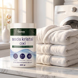 Soda Kristal Oxi 800 gr kutusu katlanmış beyaz havluların yanında