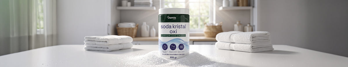 Katlanmış beyaz havluların arasında, dökülmüş toz üzerinde duran Soda Kristal Oxi kutusu